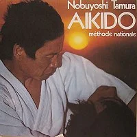 Couverture d’Aïkido – Méthode nationale : Tamura en keikogi blanc, titre en blanc et orange